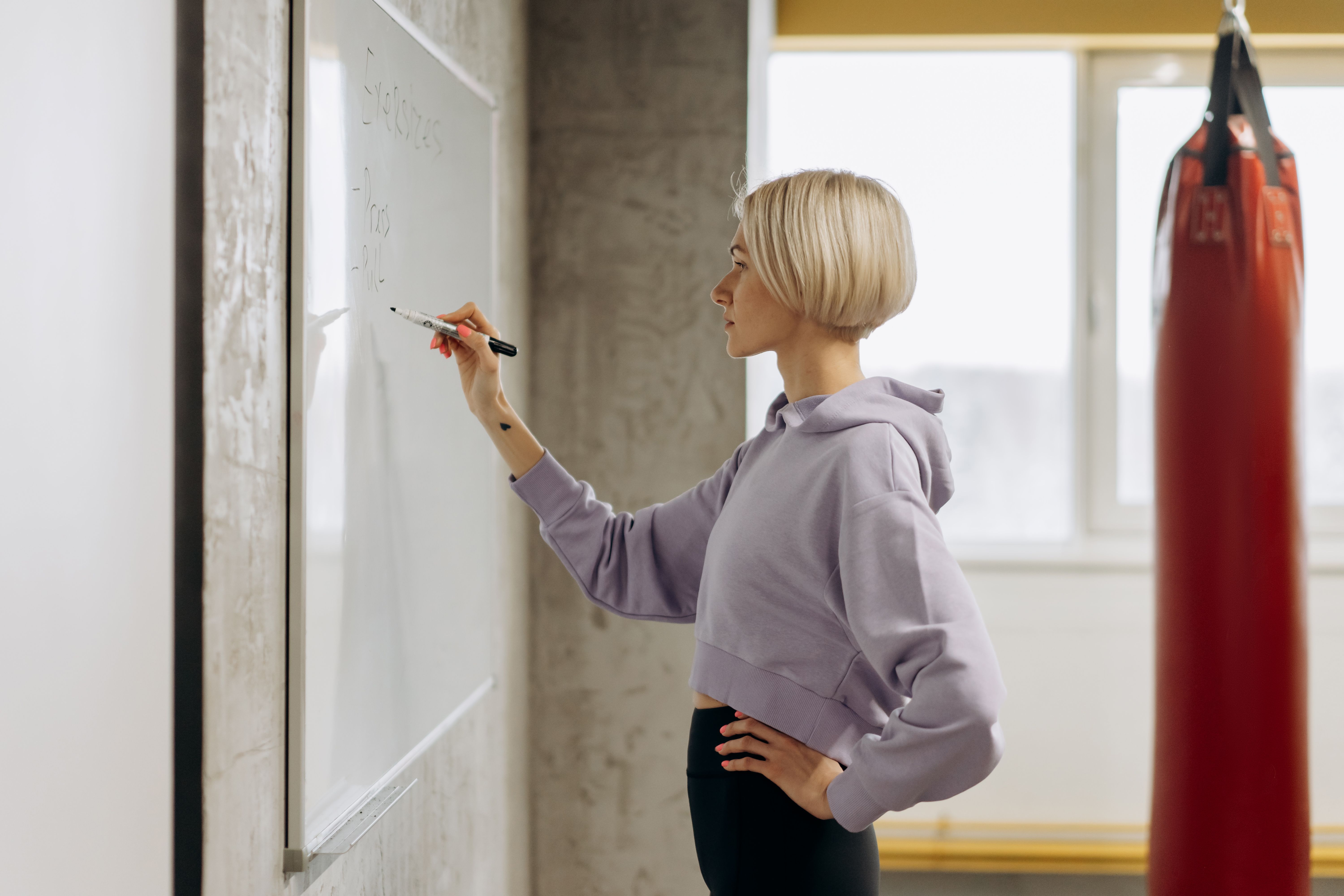 Personal trainer writing a workout plan on a whiteboard in a gym